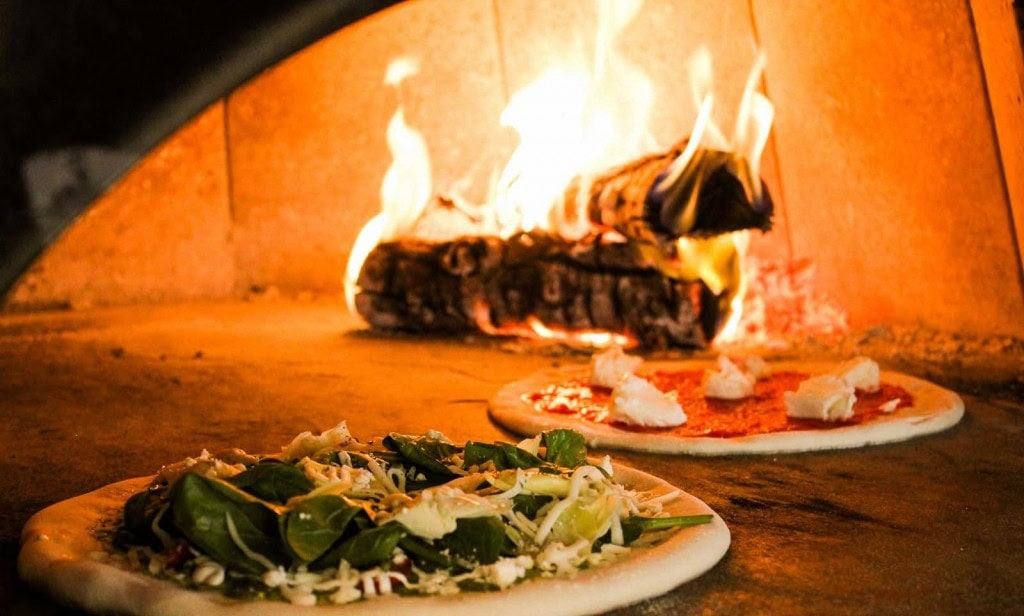 Wood fired pizza baking in a brick oven at Elemental Pizza Seattle